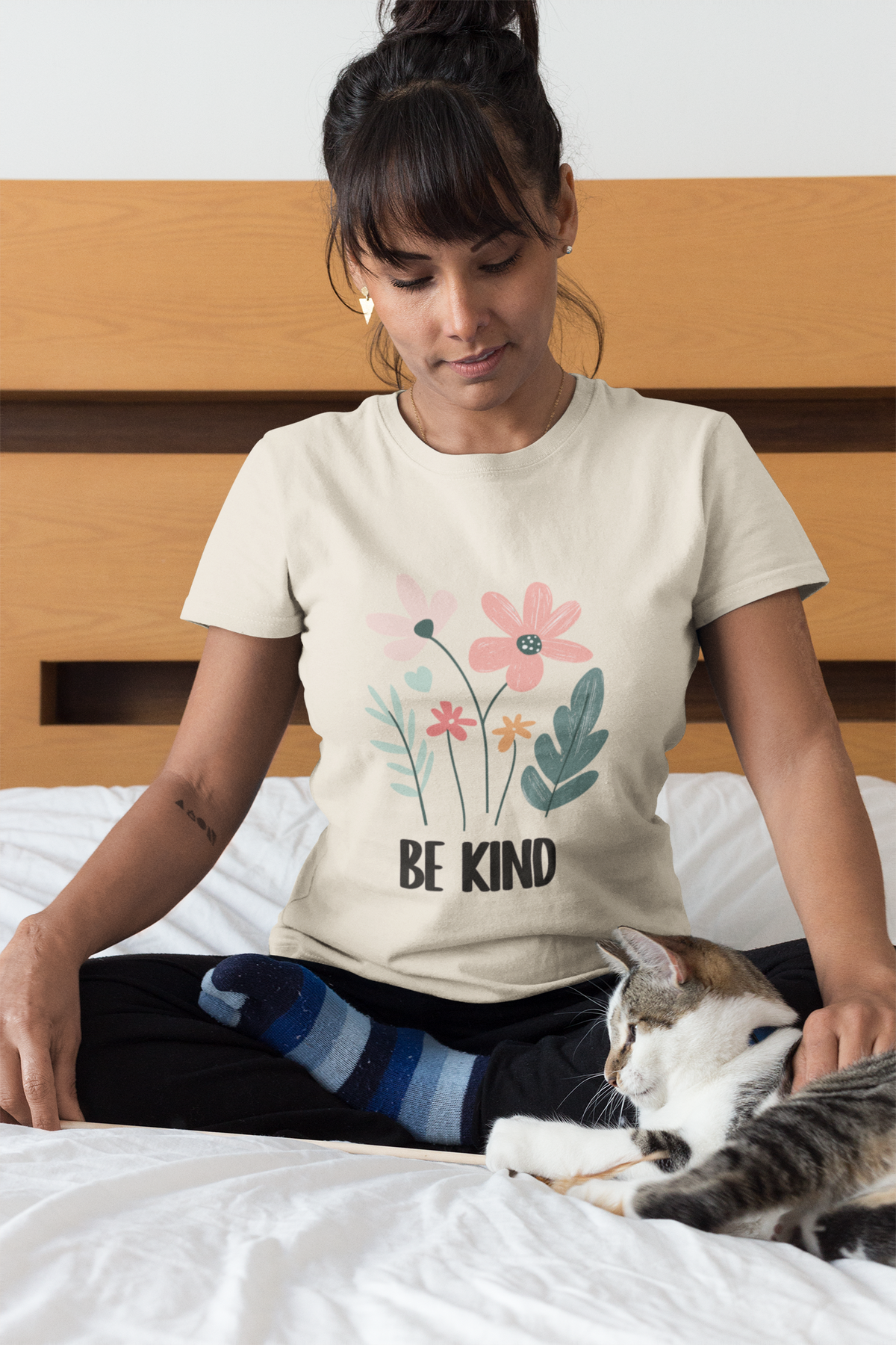  Lifestyle shot with model wearing the floral “Be Kind” motif in a  natural tee un a relaxed scene.