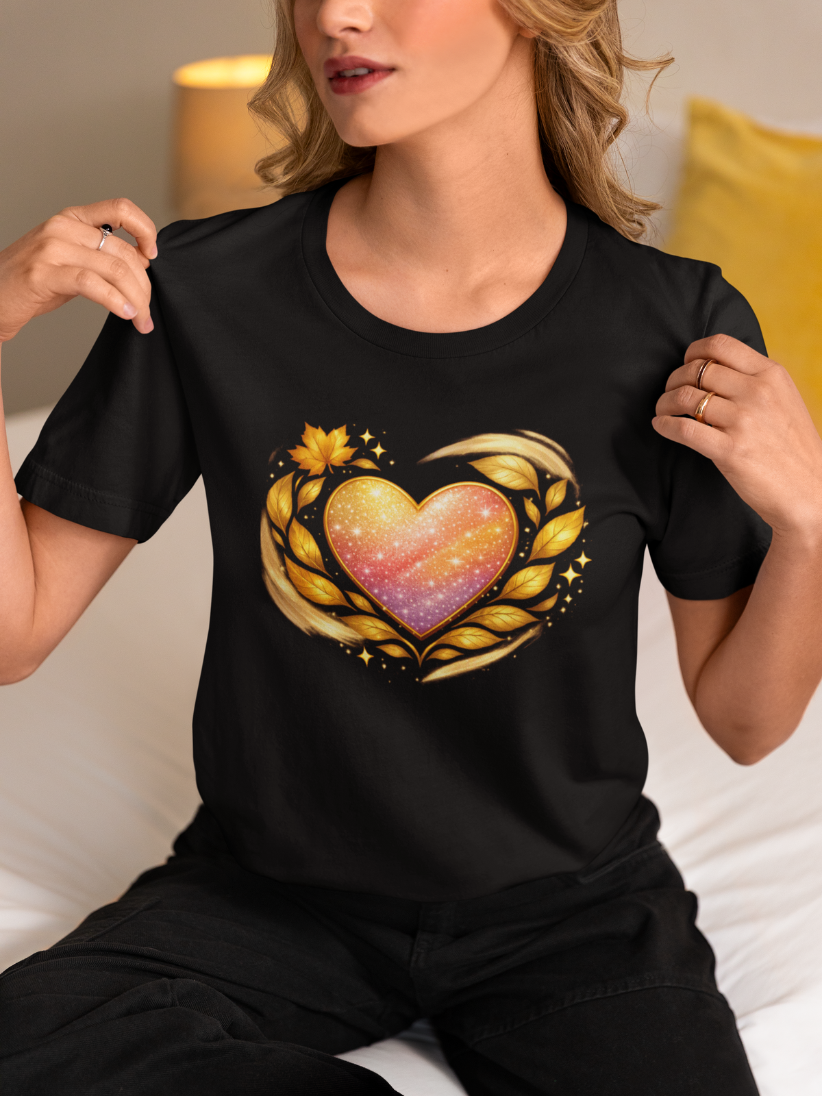 Woman wearing black T‑shirt featuring a gradient heart with gold leaf accents printed on the front.