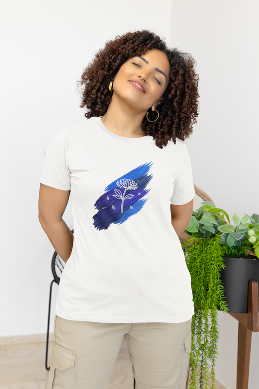 Model wearing the white Blue Brushstroke Lotus Tee with a soft blue paint background and white lotus line‑art.