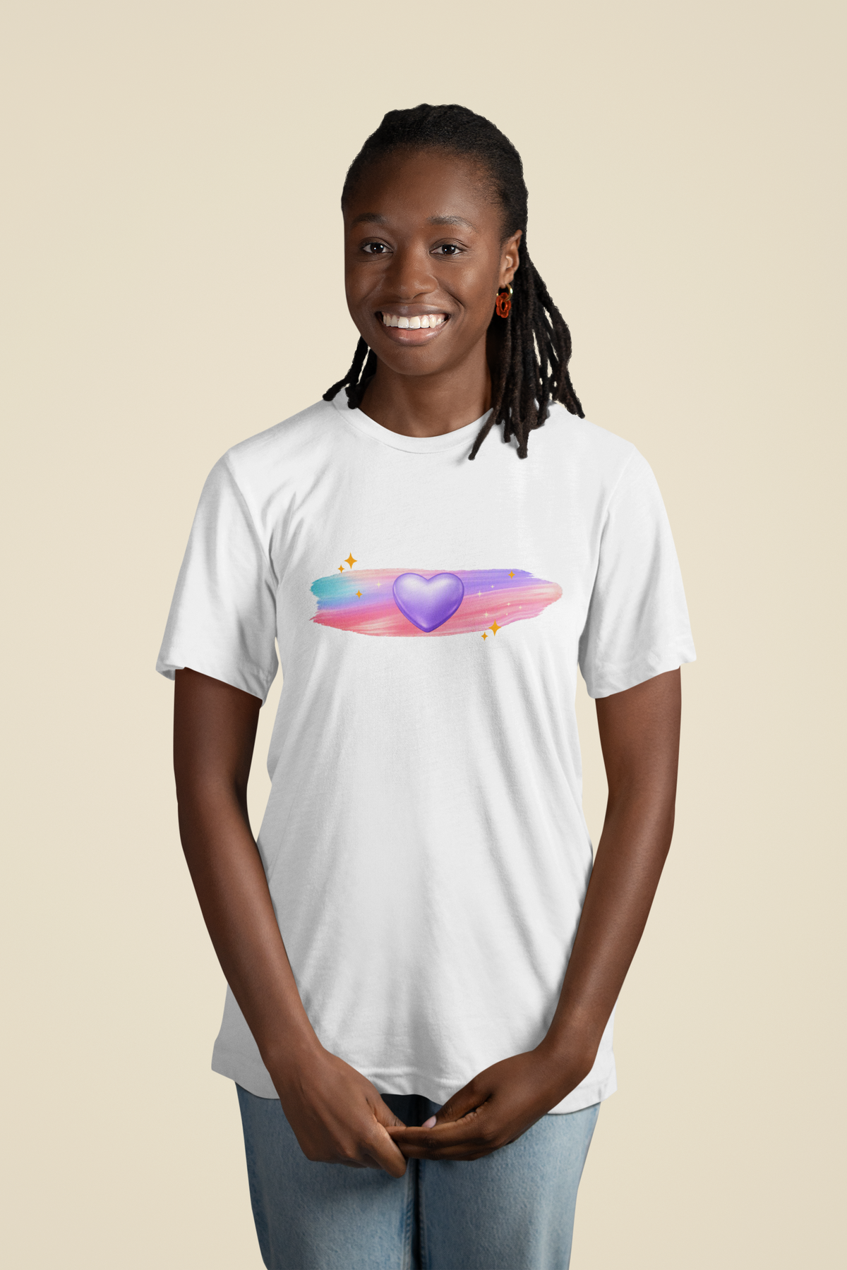 Woman wearing a white t‑shirt featuring a glowing purple heart with pastel brushstrokes and subtle sparkle accents.