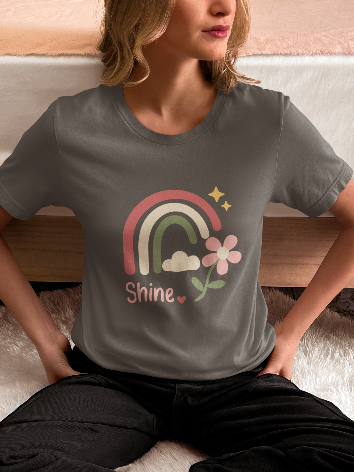 Model wearing the asphalt Shine Pastel Rainbow Tee featuring a pastel rainbow with stars and a floral accent.