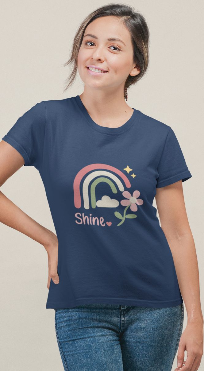 Model wearing the navy Shine Pastel Rainbow Tee with a pastel rainbow, soft stars, and floral accent.