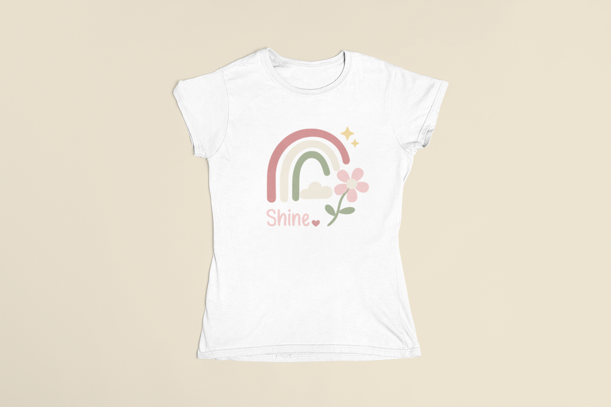 White Shine Pastel Rainbow Tee in a flat‑lay display showing the pastel rainbow, stars, and floral accent.