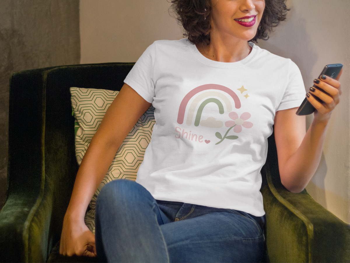 Model wearing the white Shine Pastel Rainbow Tee with a pastel rainbow, soft stars, and floral accent.