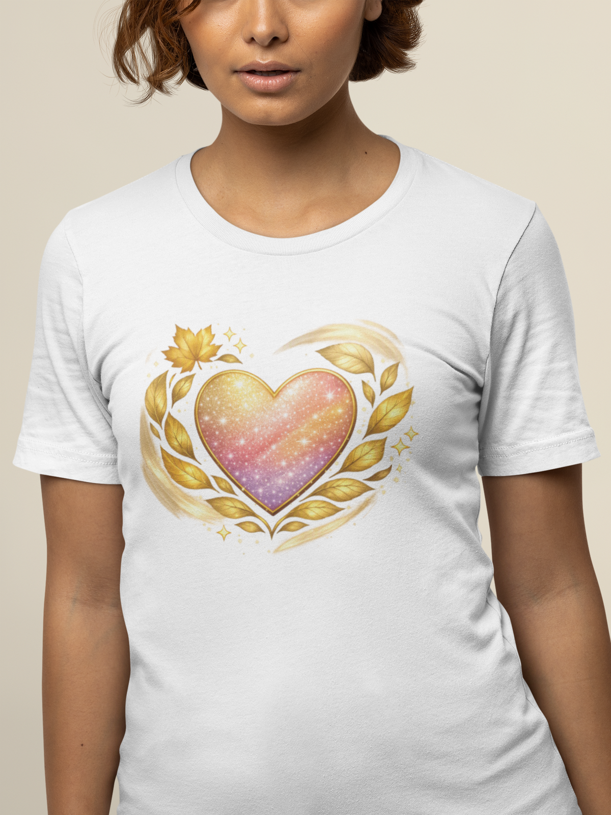 Woman wearing white T‑shirt featuring a gradient heart with gold leaf accents printed on the front.